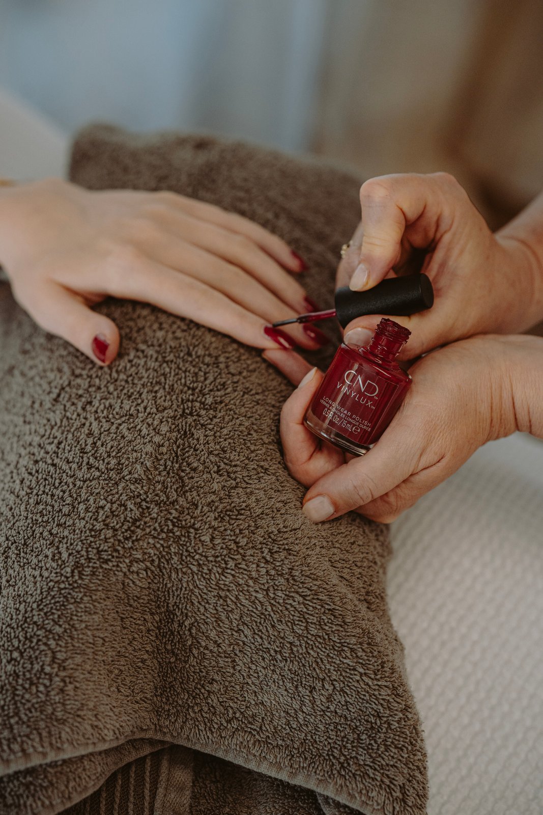 Bei einer Maniküre wird roter Nagellack aufgetragen